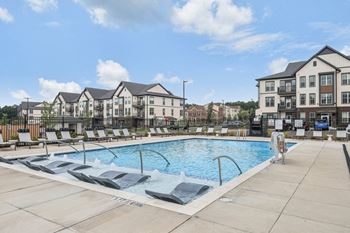 a swimming pool with lounge chairs in front of an apartment building at Nook Nine, Indianapolis, 46240